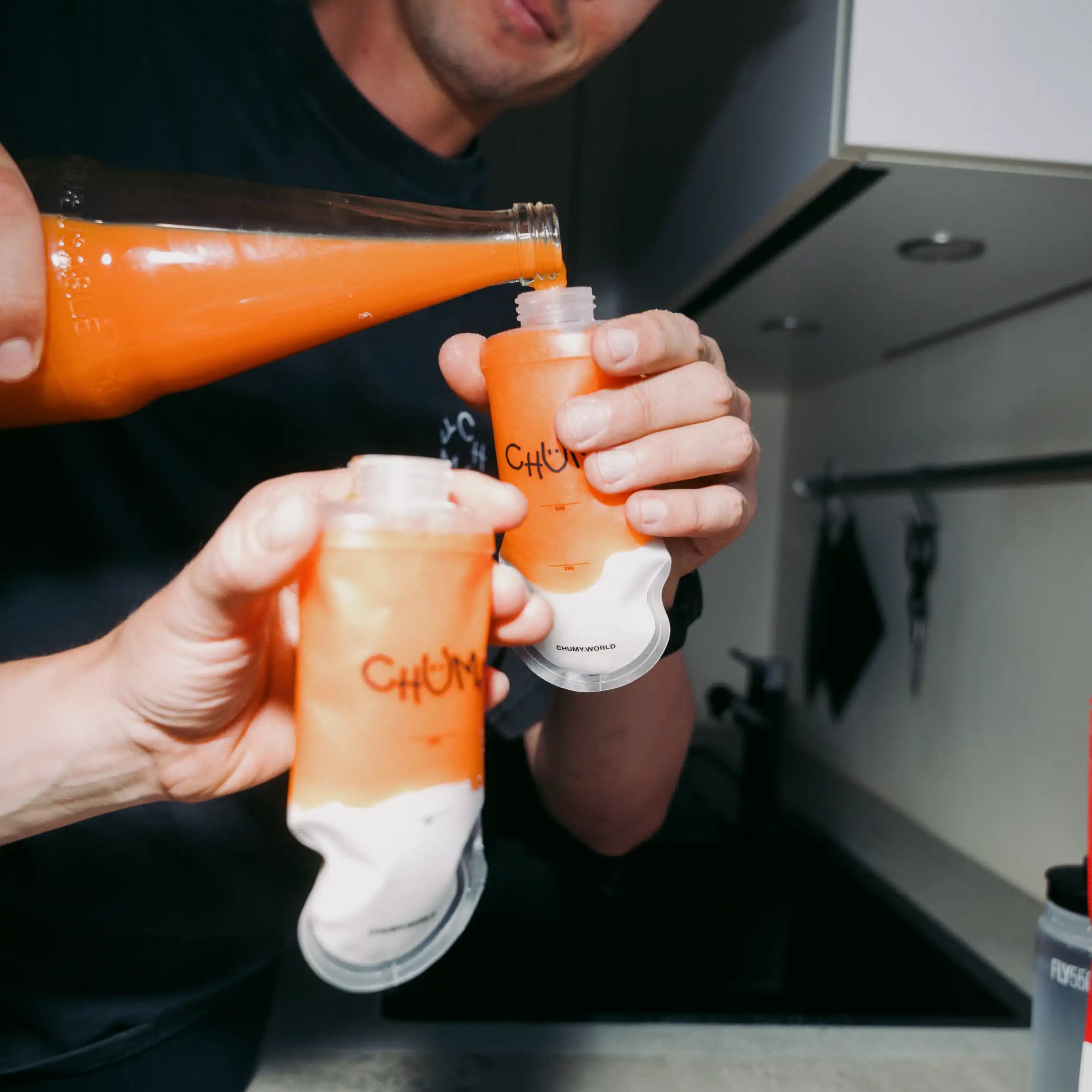 Eine Person befüllt eine wiederverwertbare nachhaltige Energy-Gel Verpackung mit Orangensaft 