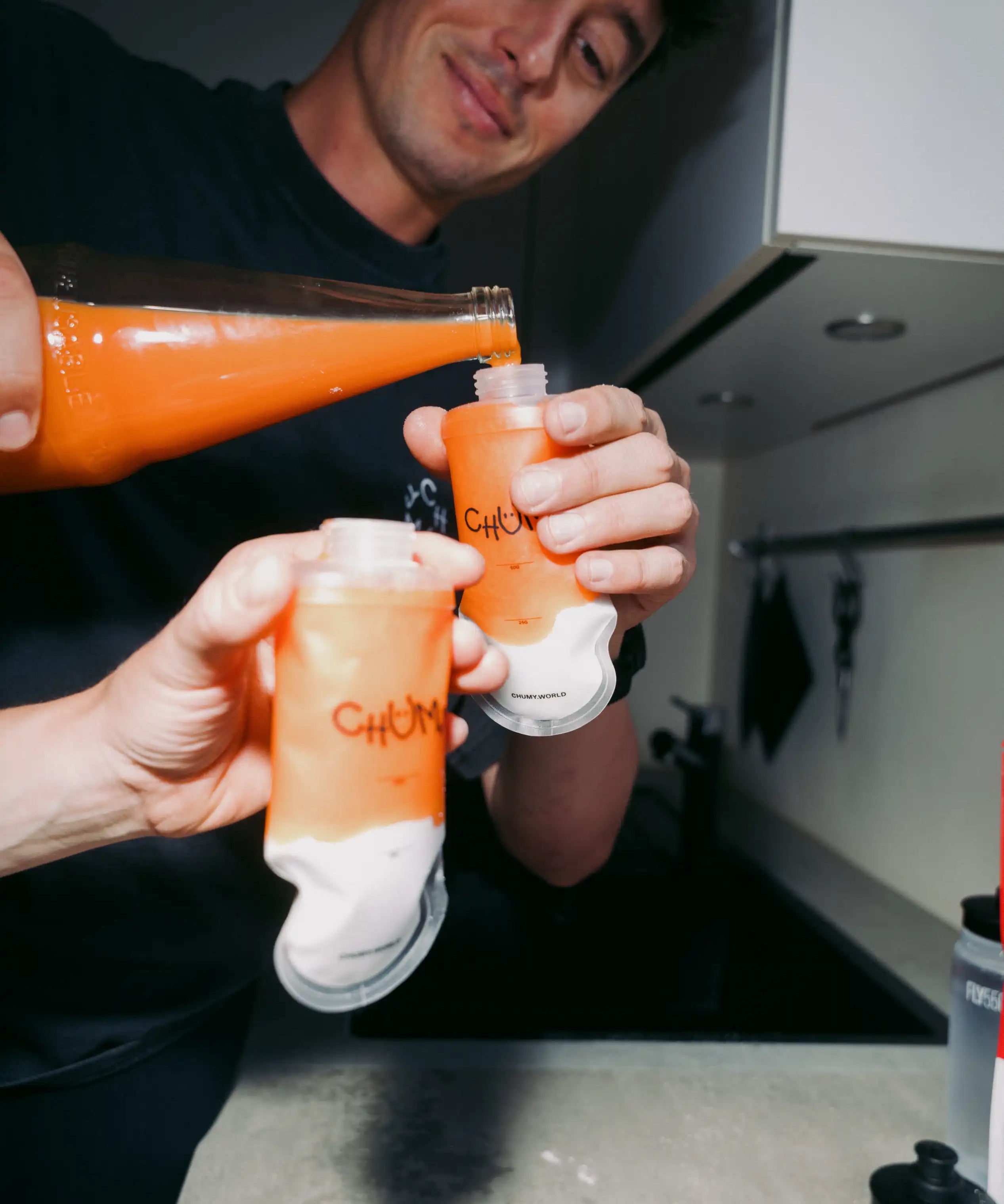 Eine Person befüllt eine wiederverwertbare nachhaltige Energy-Gel Verpackung mit Orangensaft 