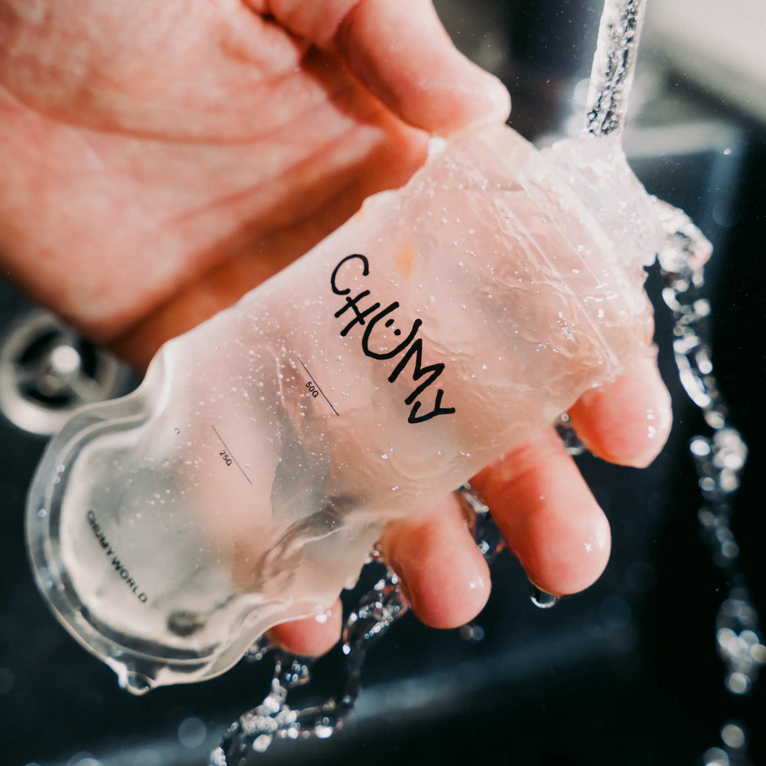 Eine Person reinigt eine wiederverwertbare nachhaltige Energy-Gel Verpackung unter klarem Wasser