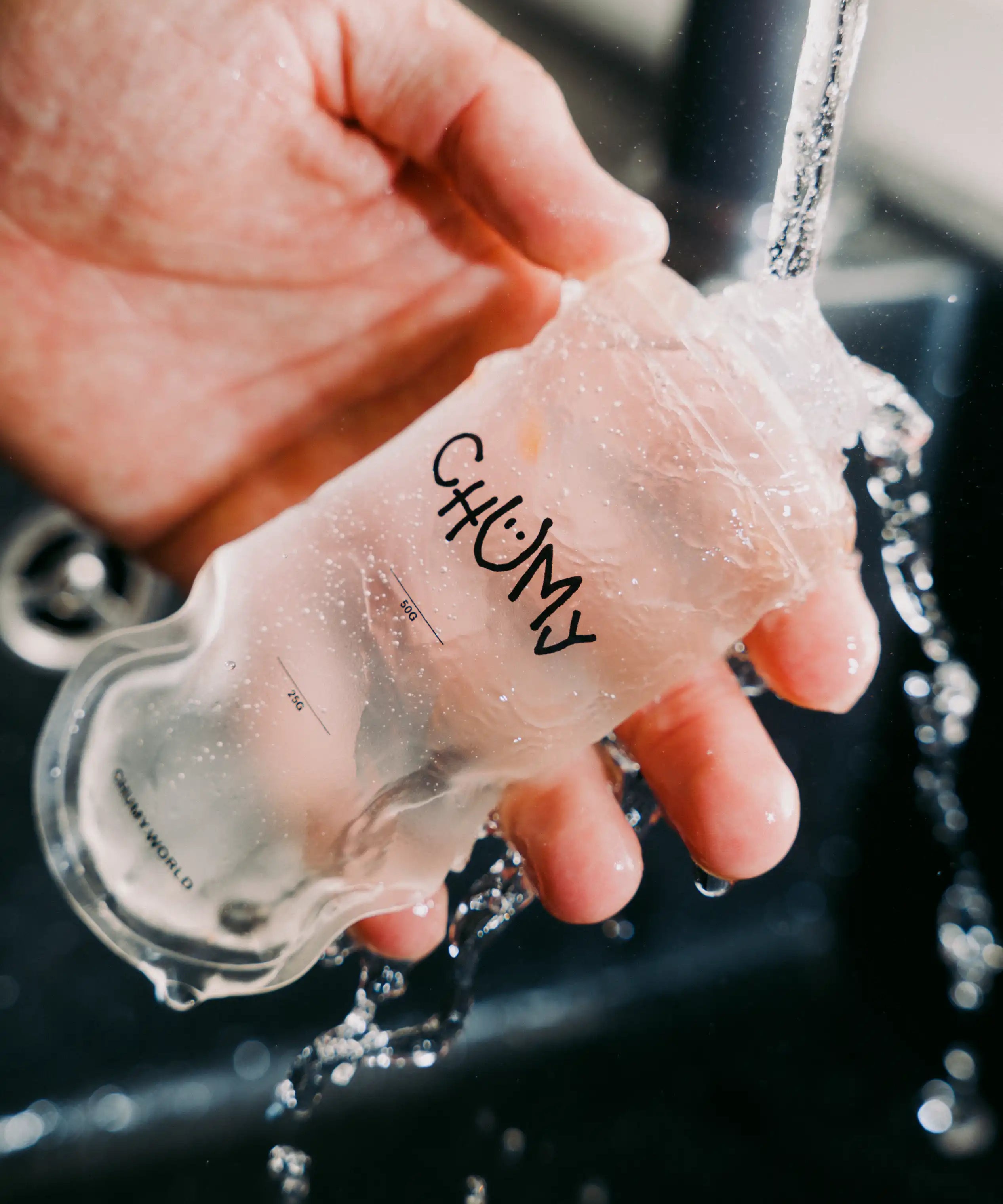 Eine Person reinigt eine wiederverwertbare nachhaltige Energy-Gel Verpackung unter klarem Wasser