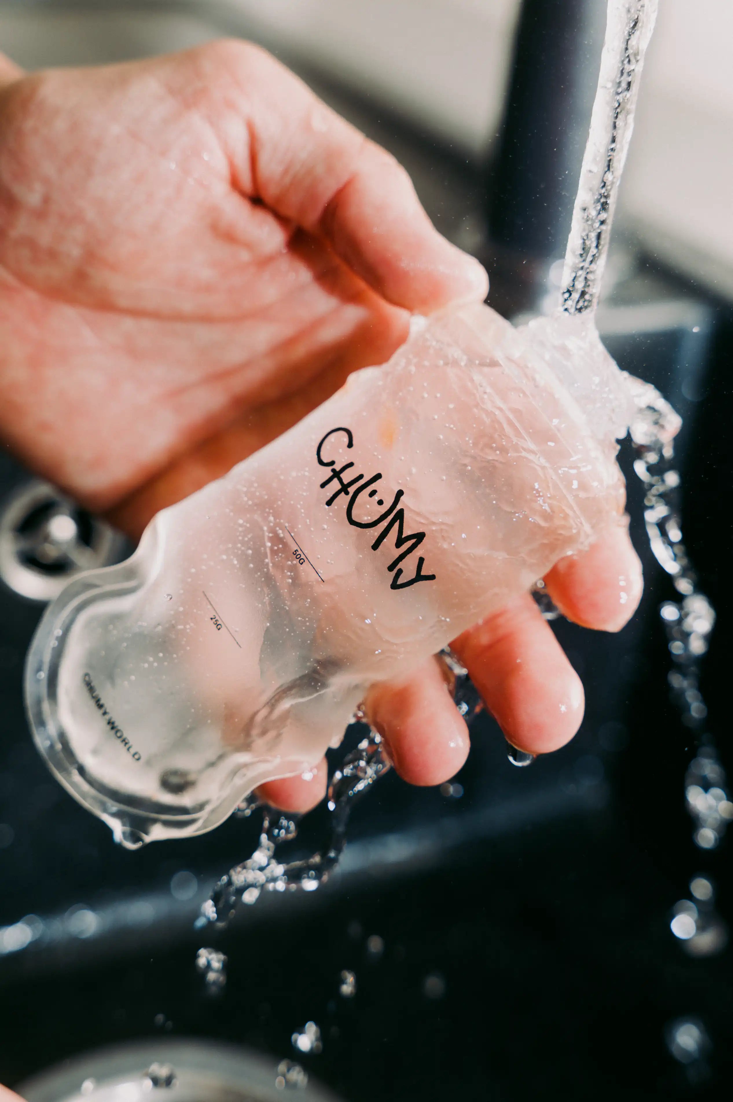 Eine Person reinigt eine wiederverwertbare nachhaltige Energy-Gel Verpackung unter klarem Wasser