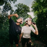 Ein Radfahrer und eine Radfahrerin trinken nachhaltiges Energy-Gel in einem Wald bei einer Gravel Ausfahrt