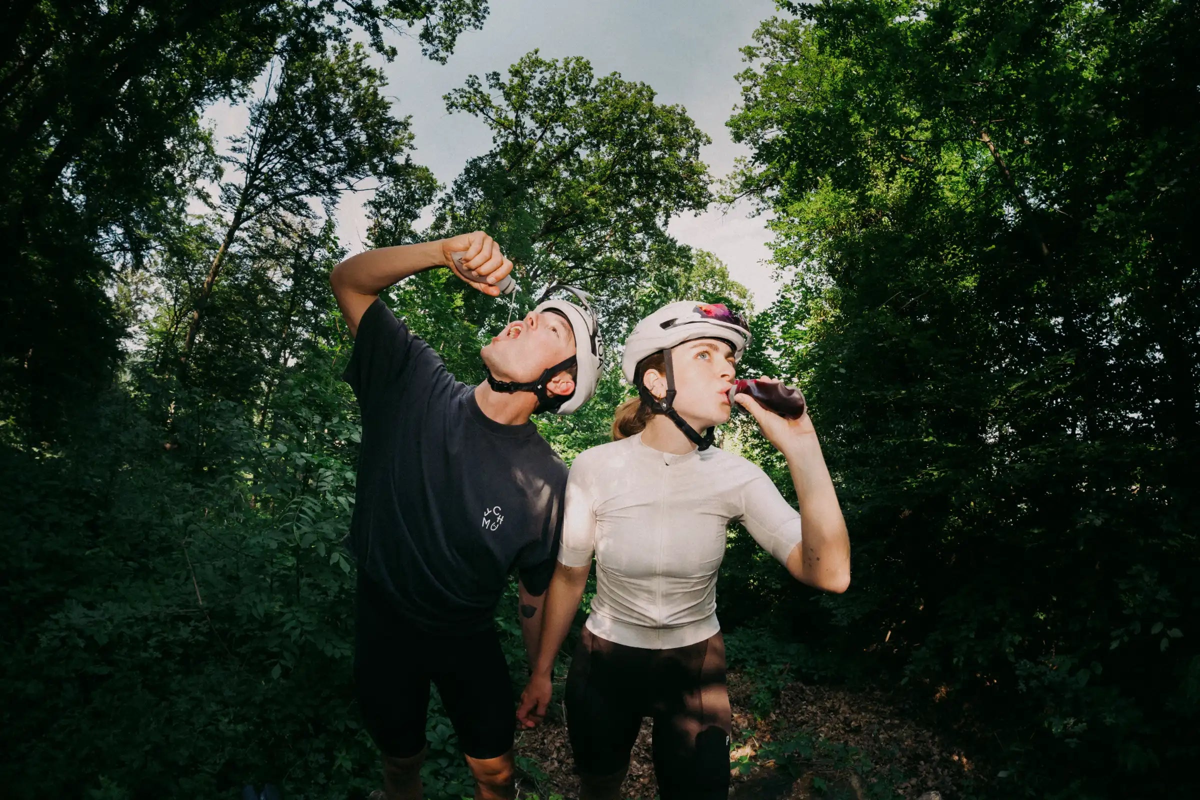 Ein Radfahrer und eine Radfahrerin trinken nachhaltiges Energy-Gel in einem Wald bei einer Gravel Ausfahrt